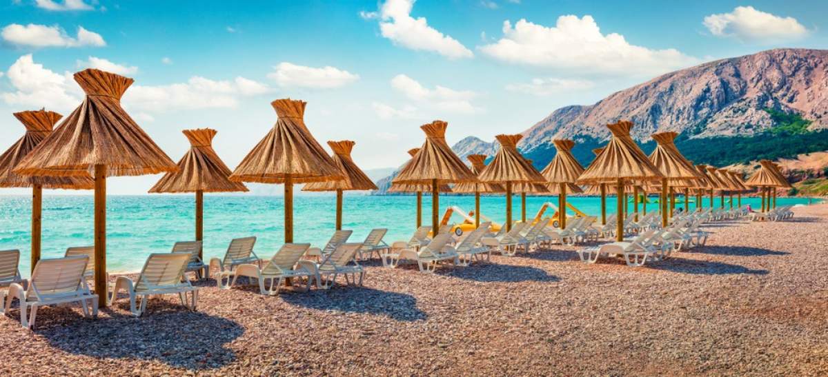 Umbrellas and sunbeds on the beach in Baška